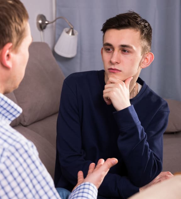 A photo of a man and his teenage son having a serious chat at home