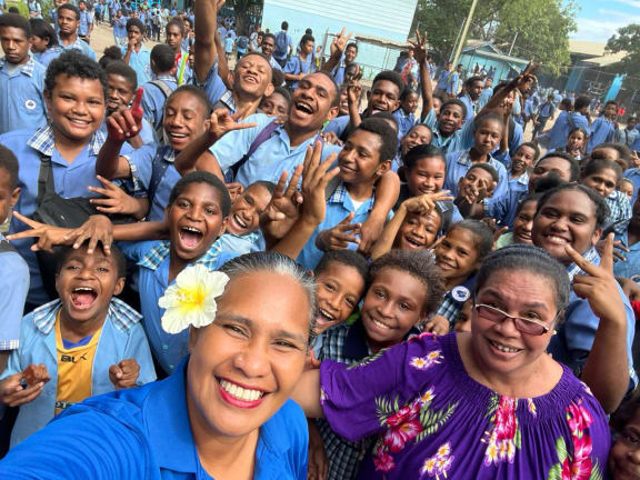 Kiwi F.C Coach Leti Tamasese poses with school children in Port Moresby, Papua New Guinea