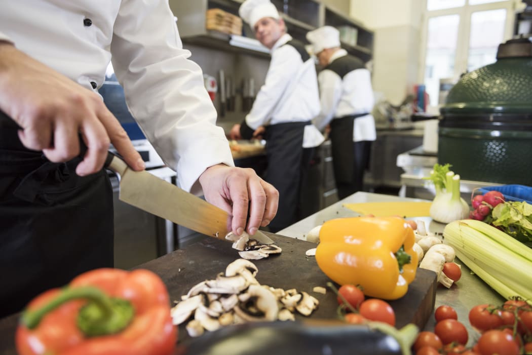 A group of people cooking in a commercial kitchen.