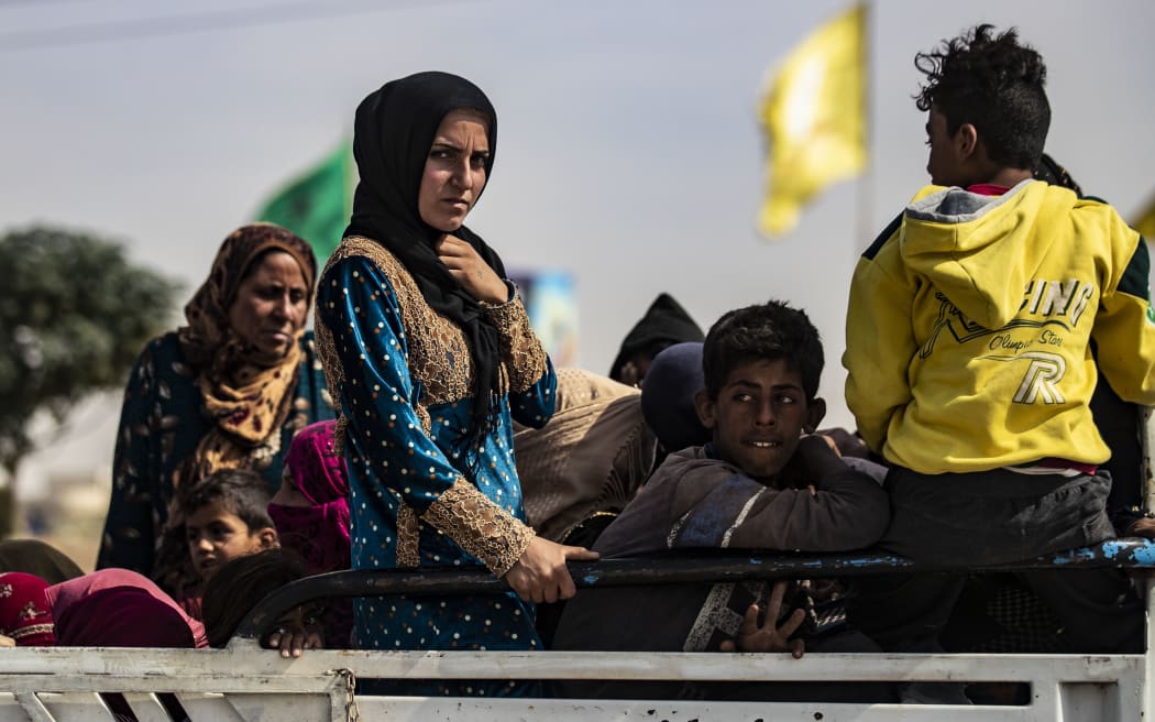 Displaced Syrians sit in the back of a pick up truck as Arab and Kurdish civilians flee amid Turkey's military assault on Kurdish-controlled areas in northeastern Syria, on October 11, 2019 in the town of Tal Tamr in the countryside of Syria's northeastern Hasakeh province.