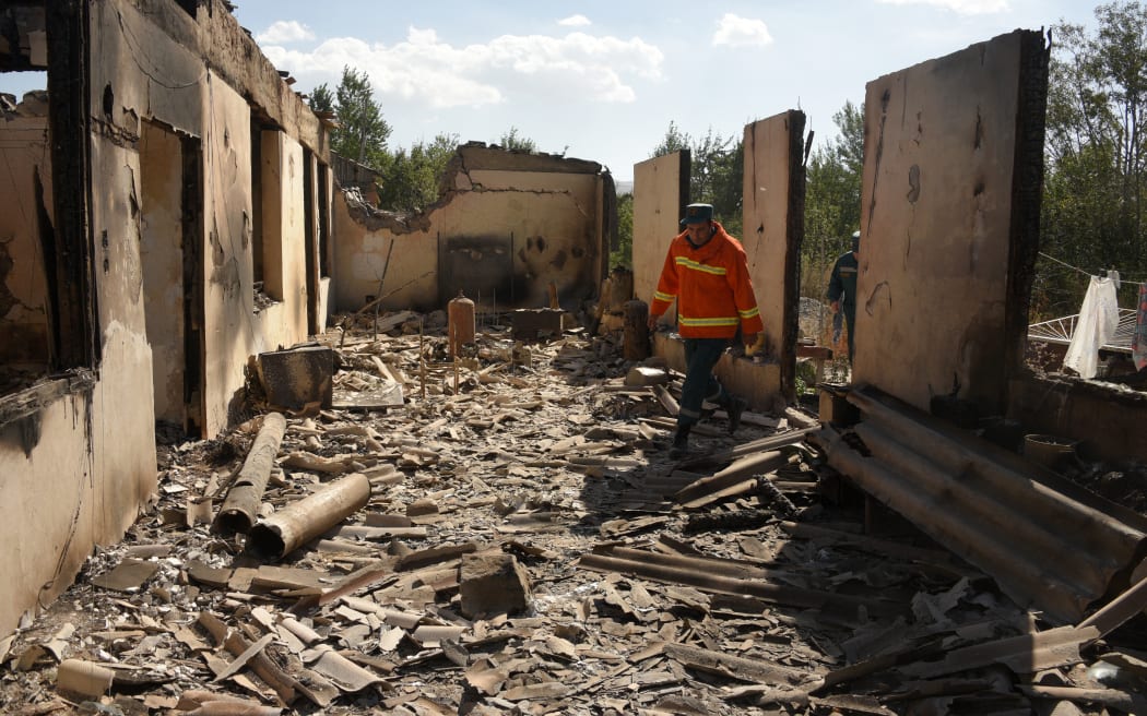 Firefighters work among the ruins of a house, which is said was hit by Azeri shelling during recent border clashes with Azerbaijan, in the settlement of Sotk, Armenia.