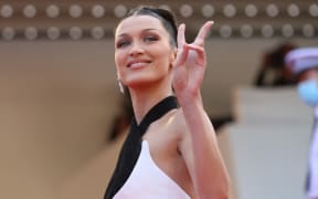US model Bella Hadid flashes the victory sign as she arrives for the opening ceremony and the screening of the film 'Annette' at the 74th edition of the Cannes Film Festival in Cannes, southern France, on July 6, 2021.