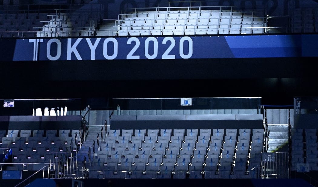 A spotlight highlights empty seats in the stadium ahead of the women's 3m springboard diving final event during the Tokyo 2020 Olympic Games at the Tokyo Aquatics Centre in Tokyo on August 1, 2021. (Photo by Attila KISBENEDEK / AFP)