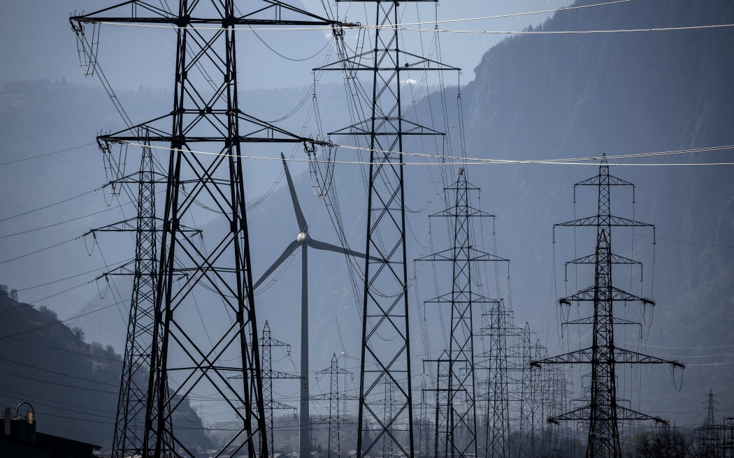 A wind turbine is surrounded by electricity pylons near Evionnaz, Canton of Valais, western Switzerand on March 28, 2022. - (Photo by Fabrice COFFRINI / AFP)