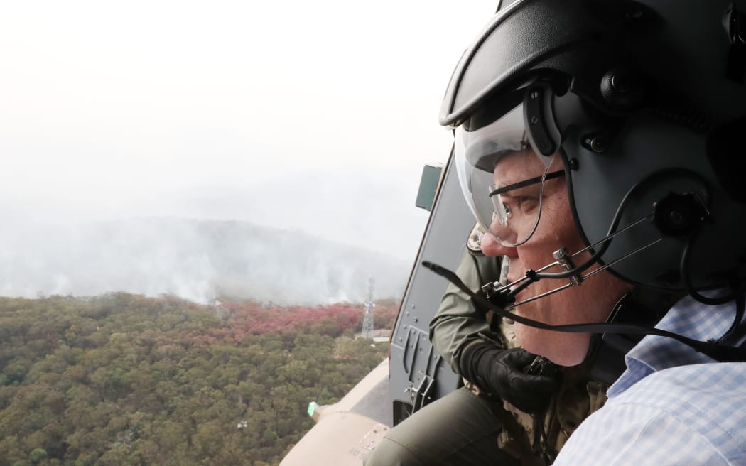 This handout photograph taken and released on December 23, 2019 by the Australian Prime Minister's Office shows Australia's Prime Minister Scott Morrison flying over bushfires in an Australian Defence Force helicopter in New South Wales.