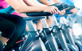 Group of four people spinning in the gym, as they take part in a HIIT class.