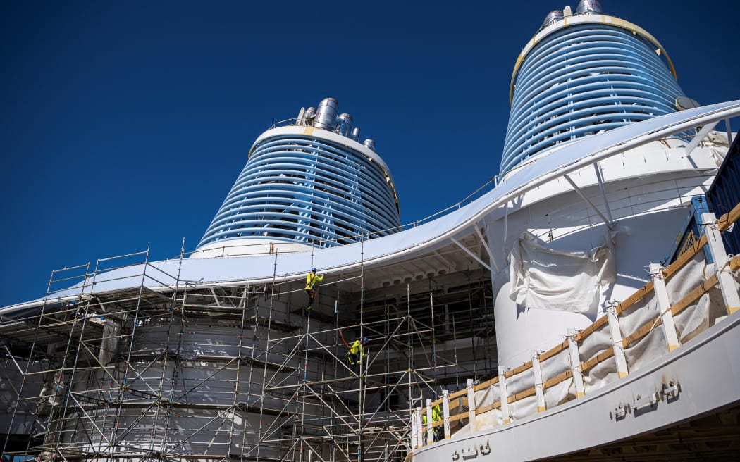 Workers are seen on scaffolding at the construction site below the chimneys of the Royal Caribbean's new ship 'Icon of the Seas' at the Turku shipyard in Finland's southwest coast on May 30, 2023.