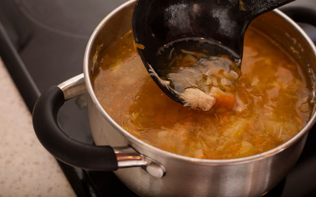 Chicken soup in a saucepan on the stove.