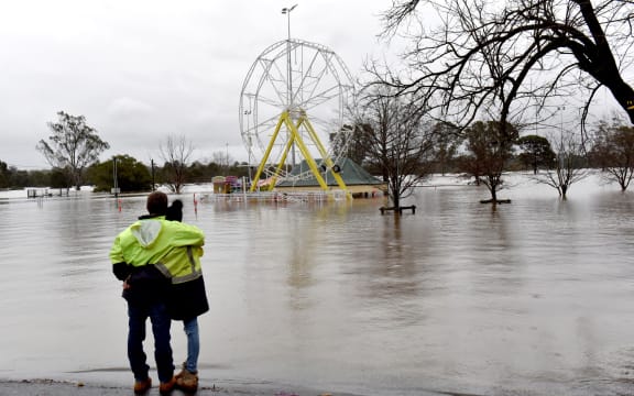People look at a flooded park due to torrential rain in the Camden suburb of Sydney on July 3, 2022. - Thousands of Australians were ordered to evacuate their homes in Sydney on July 3 as torrential rain battered the country's largest city and floodwaters inundated its outskirts. (Photo by Muhammad FAROOQ / AFP)
