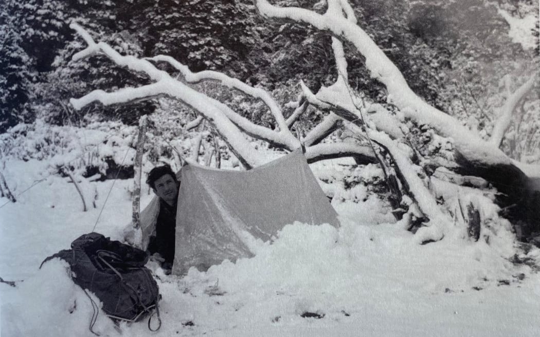 Frank partially buried under snow in his tent while out on a hunt.