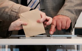 Casting a vote at a ballot box.