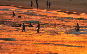 Beachgoers enjoy the sunset at Bondi beach during a heatwave in Sydney on December 19, 2019. A state of emergency was declared in Australia's most populated region on December 19 as an unprecedented heatwave fanned out-of-control bushfires, destroying homes and smothering huge areas with a toxic smoke. (Photo by FAROOQ KHAN / AFP)