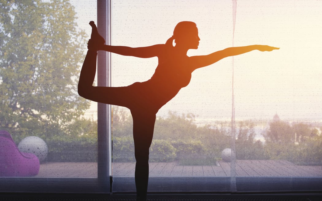 Silhouette of woman doing yoga at home at sunset. (Science Photo Library via AFP)
