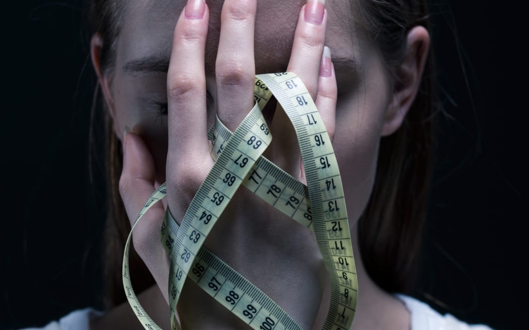 Anorexic girl covering her face with a centimeter