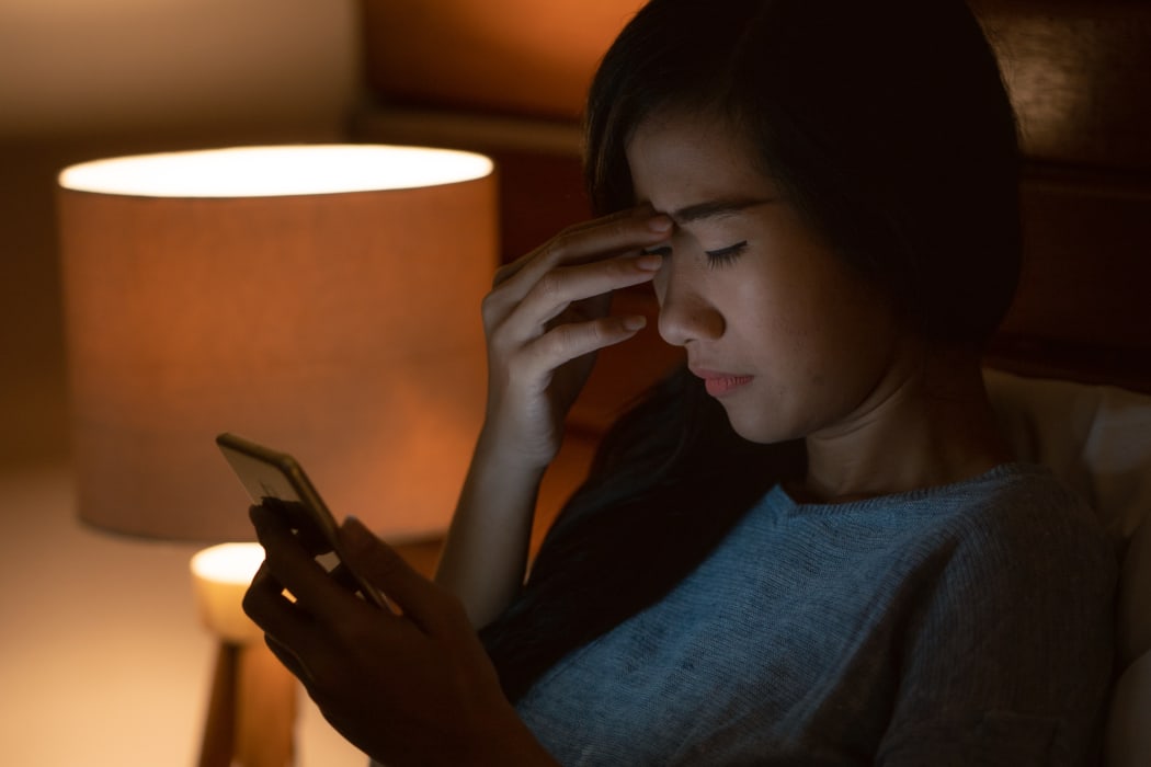 unhappy girl feeling sad reading bad news in smartphone on bed