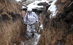 A Ukrainian serviceman walks along a snow covered trench on the front line with the Russia-backed separatists near Verkhnetoretskoye, in the Donetsk region on 1 February 2022.