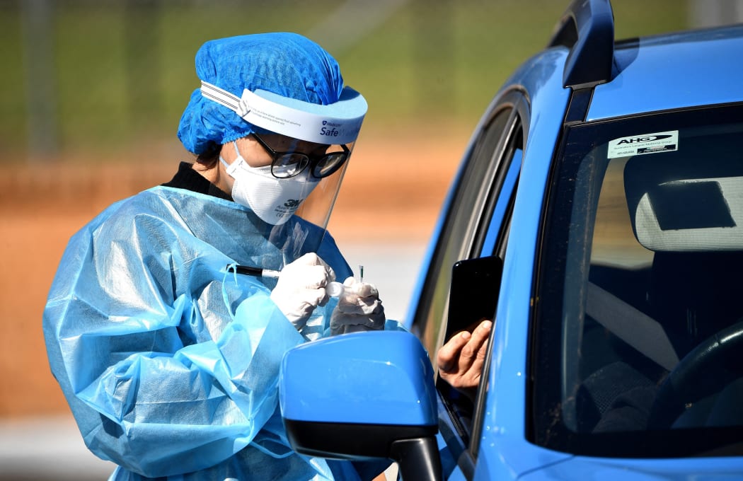A health worker takes a swab sample at a Covid-19 coronavirus drive through testing site in the Smithfield suburb of Sydney on August 12, 2021.