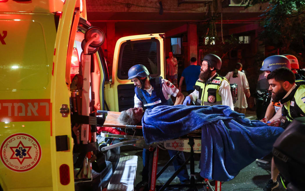 EDITORS NOTE: Graphic content / Israeli first responders evacuate an injured resident from a site hit by a missile fired from Iran, in Ramat Gan on the outskirts of Tel Aviv on June 13, 2025. Iran fired a barrage of ballistic missiles at Israel in a counter-strike on June 13, after an unprecedented onslaught hammered the Islamic republic's top military brass and targeted its nuclear facilities and bases. (Photo by GIL COHEN-MAGEN / AFP)