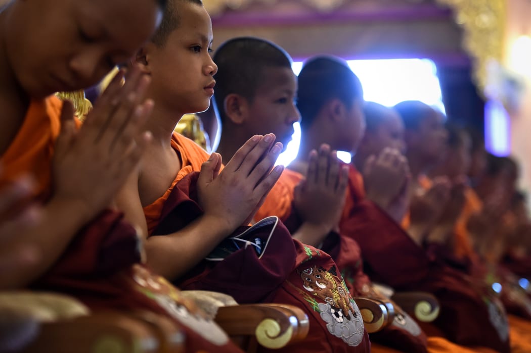 Members of the "Wild Boars" football team sit with embroidered bags of a boar playing football during a ceremony to mark the end of the players' retreat as novice Buddhist monks at the Wat Phra That Doi Tung temple in the Mae Sai district of Chiang Rai province.