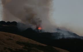 As night falls, flames from the Port Hills fire on 14/2/2024 become more apparent.