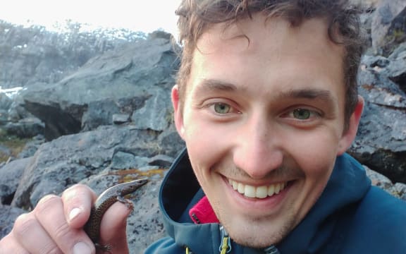 Sam Purdie holding an awakōpaka skink