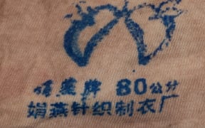 A brand's emblem on a light-coloured singlet found on the body of a woman found dead in Gulf Harbour on 12 March, 2024.