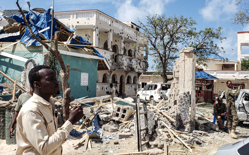 A man passes in front of the rubbles of the popular Medina hotel of Kismayo on July 13, 2019, a day after at least 26 people, including several foreigners, were killed and 56 injured in a suicide bomb and gun attack claimed by Al-Shabaab militants.