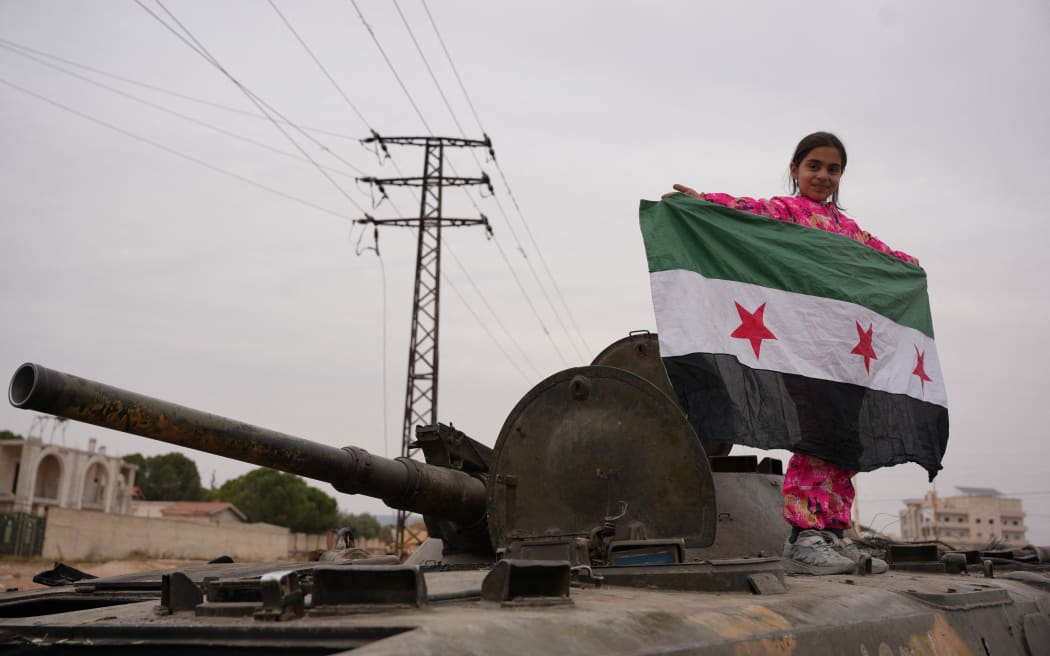 Celebrations in the city of Hama, where Syrians gather at Al-Assi Square to take commemorative photos and express their joy over the city's control. The square is filled with the sounds of celebratory gunfire and the distribution of sweets to mark the occasion.