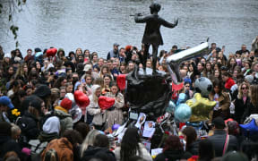Fans of former One Direction singer Liam Payne gather with balloons and flowers beside the Peter Pan statue in Kensington Gardens, adjacent to Hyde Park for a memorial following the singer's death earlier in the week, in London on October 20, 2024. - Payne, fell from a third-floor hotel balcony in Buenos Aires, the  Argentinian capital on Wednesday. While the exact circumstances of the fall are unclear, police said they responded to a report of "an aggressive man who may be under the influence of drugs or alcohol". (Photo by JUSTIN TALLIS / AFP)
