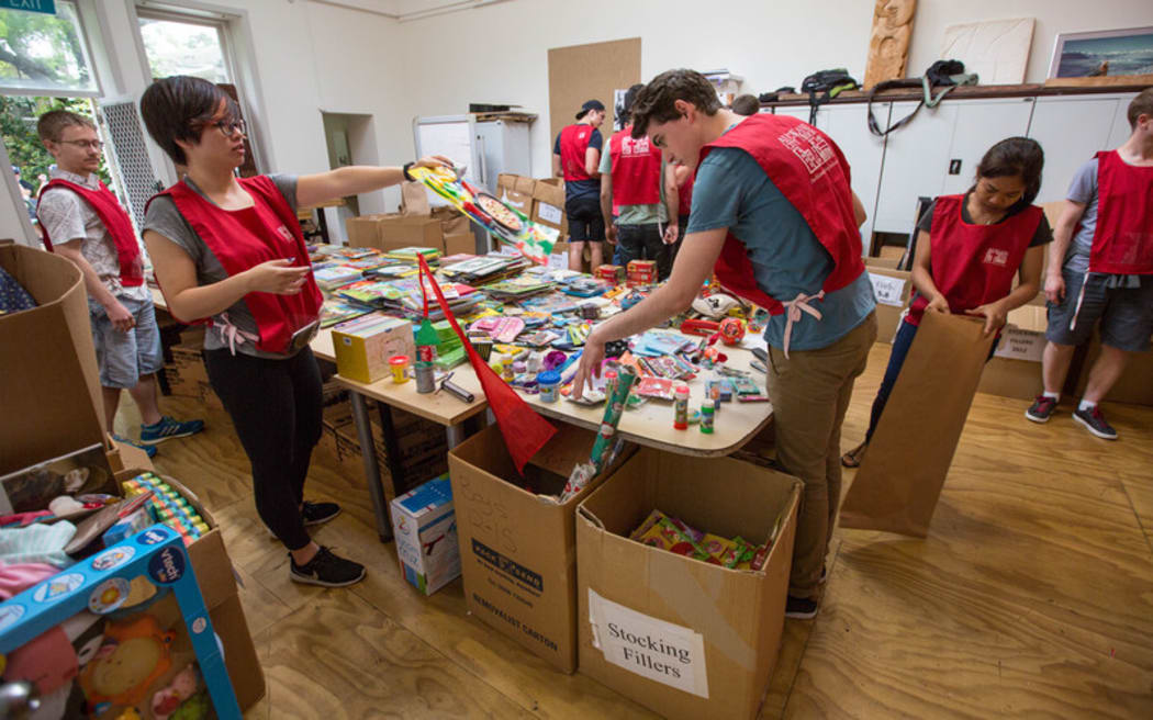 Volunteers from software company Aderant, including Ruby Yeh (foreground, left) and Ben Shaw (foreground, right), are among the volunteers preparing bags of presents for families at the Auckland City Mission today.