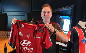 Crusaders fan Anthony Mercer hold a jersey with the team's new logo.