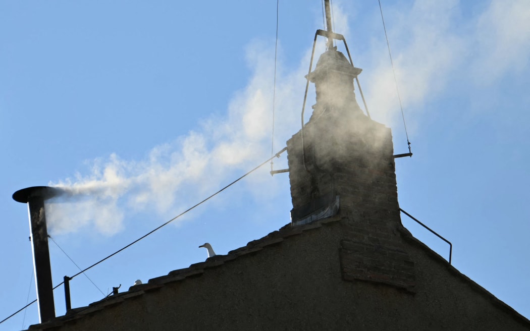 This photograph shows white smoke rising from the chinmey of the Sistine Chapel signaling that cardinals elected a new pope during their conclave in the Vatican on 8 May, 2025.