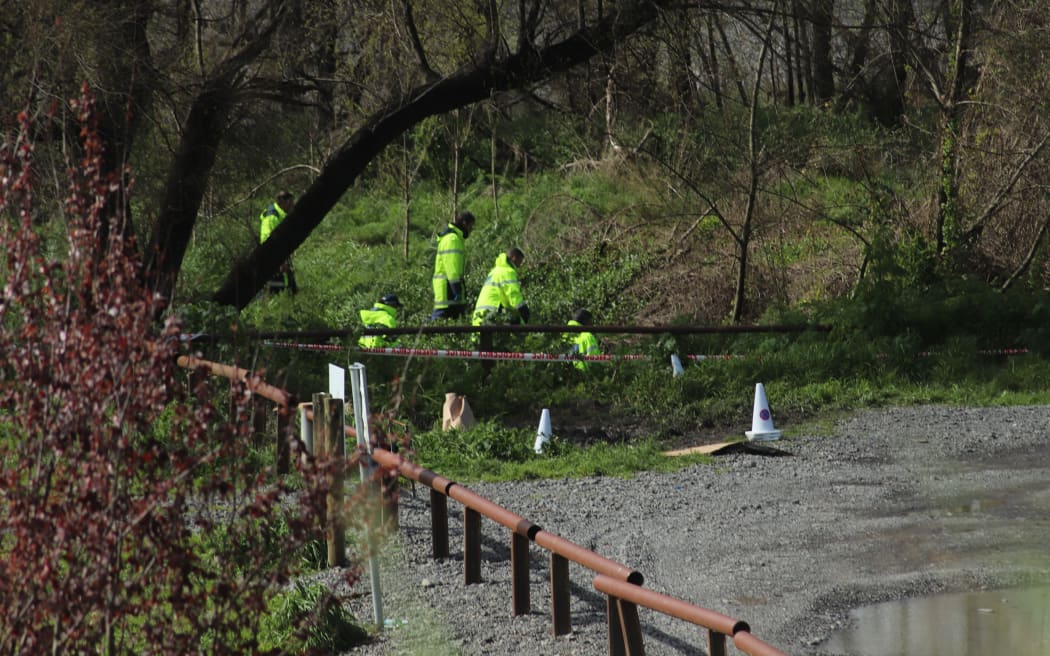 Police around the banks of the Tukituki River near Havelock North, near where a burned out car was found.