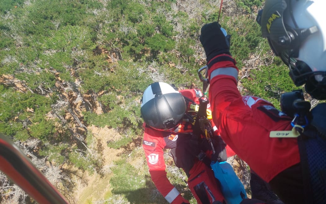 A paramedic is winched into Woodhill Forest to rescue a crashed motocross rider.