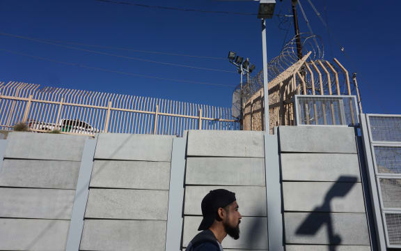 A pedestrian walks towards the port of Entry at the US-Mexico border wall.