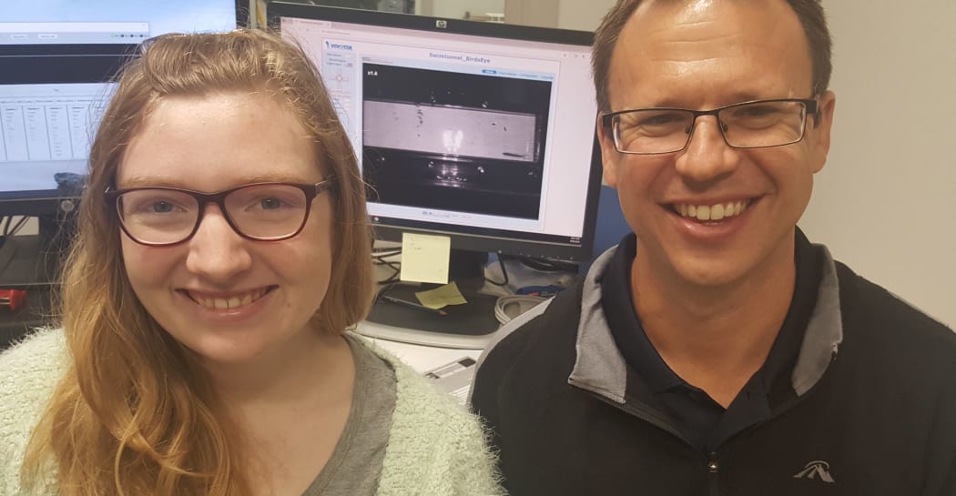Dana Nolte and Paul Franklin in front of the screen showing an inanga swimming in the flume tank.