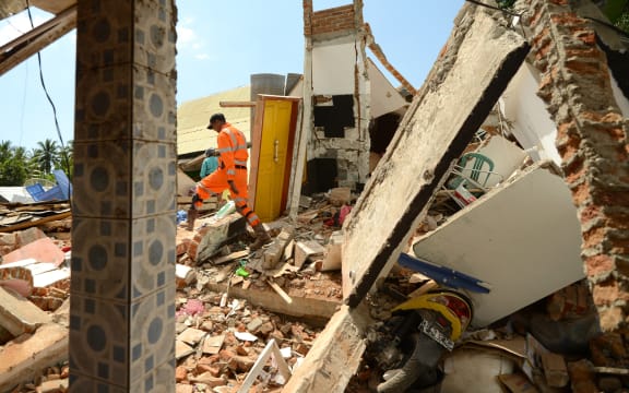 A rescue worker searches a quake damaged house at Pemenang village in northern Lombok, on 7 August, two days after the area was struck by an earthquake.