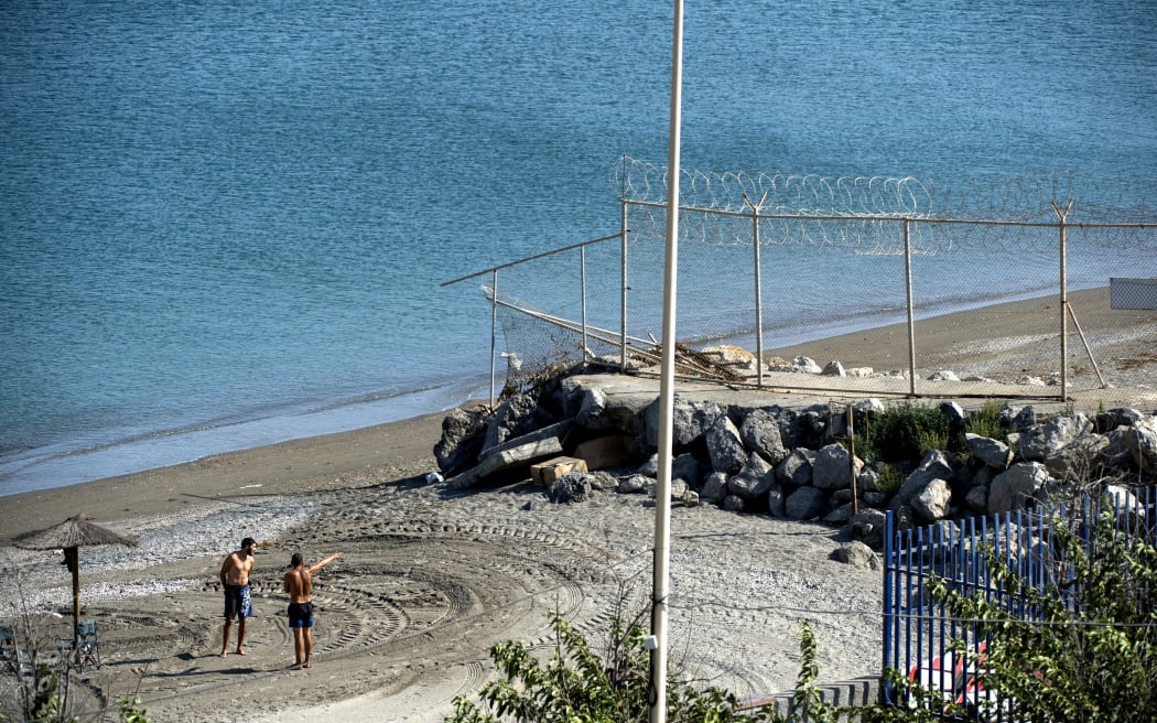 A picture taken on September 4, 2018 shows men gesturing towards a section of the border fence encircling Spain's North African enclave of Ceuta which lies on the Strait of Gibraltar, surrounded by Morocco. (Photo by FADEL SENNA / AFP)