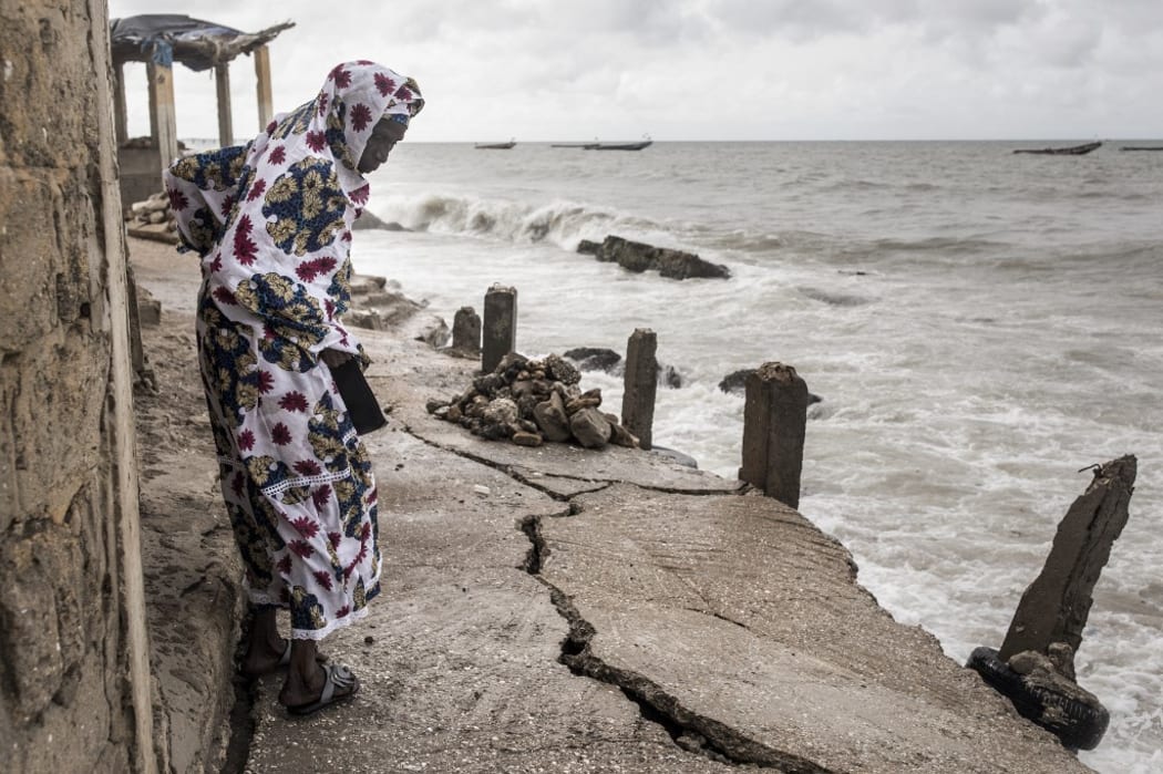 A woman looks down a newly formed crack in the walk way which leads to the Mosque in the fishing village of Bargny