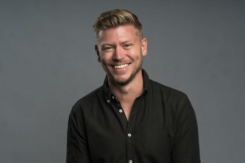 Matt Gibb is a smiling blonde haired man in a black shirt.