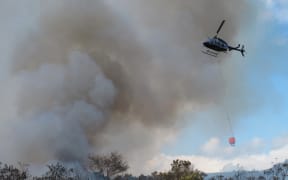 A helicopter equipped with a monsoon bucket battles an earlier fire at Mangakahia Road, south of Kaikohe (file photo).