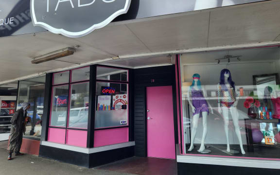 The closed pink door and shop windows on the main street running through Eketāhuna, with Tabu shop sign above