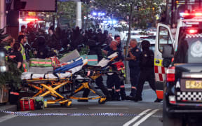 Paramedics push stretchers into the Westfield Bondi Junction shopping mall to retrieve the injured after a stabbing incident in Sydney on April 13, 2024. Australian police on April 13 said they had received reports that "multiple people" were stabbed at a busy shopping centre in Sydney. (Photo by David GRAY / AFP)