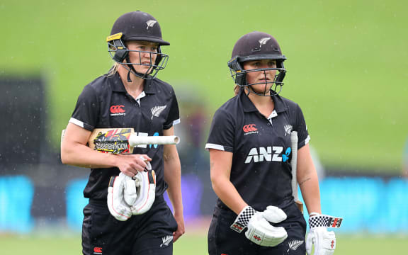 New Zealand's Maddy Green and New Zealand's Amelia Kerr leave the field as the rain sets in.