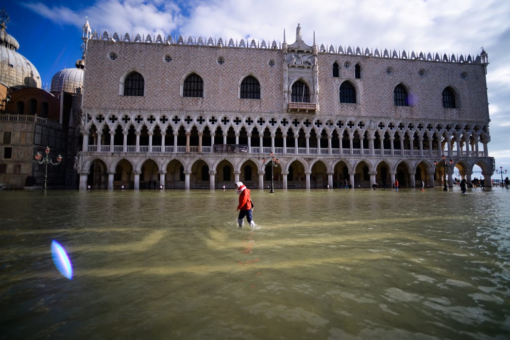 A person walks across the flooded St. Mark's Square by the Doge's palace on 14 November, 2019 in Venice.