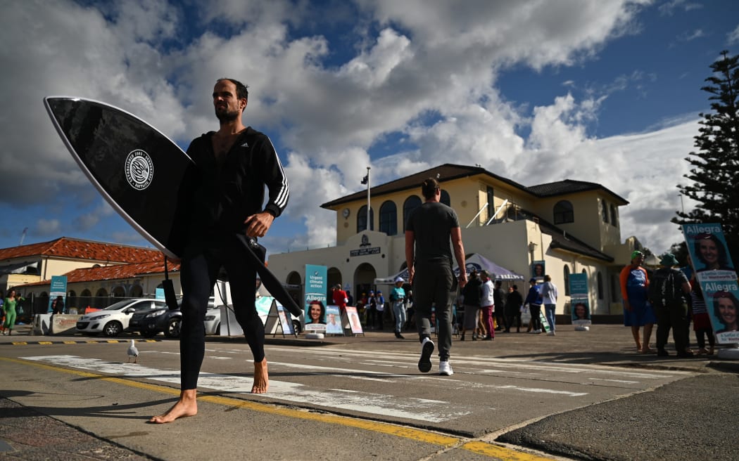 People arrive to vote during Australia's general election at a polling station at Bondi Beach in Sydney on May 21, 2022. (Photo by STEVEN SAPHORE / AFP)