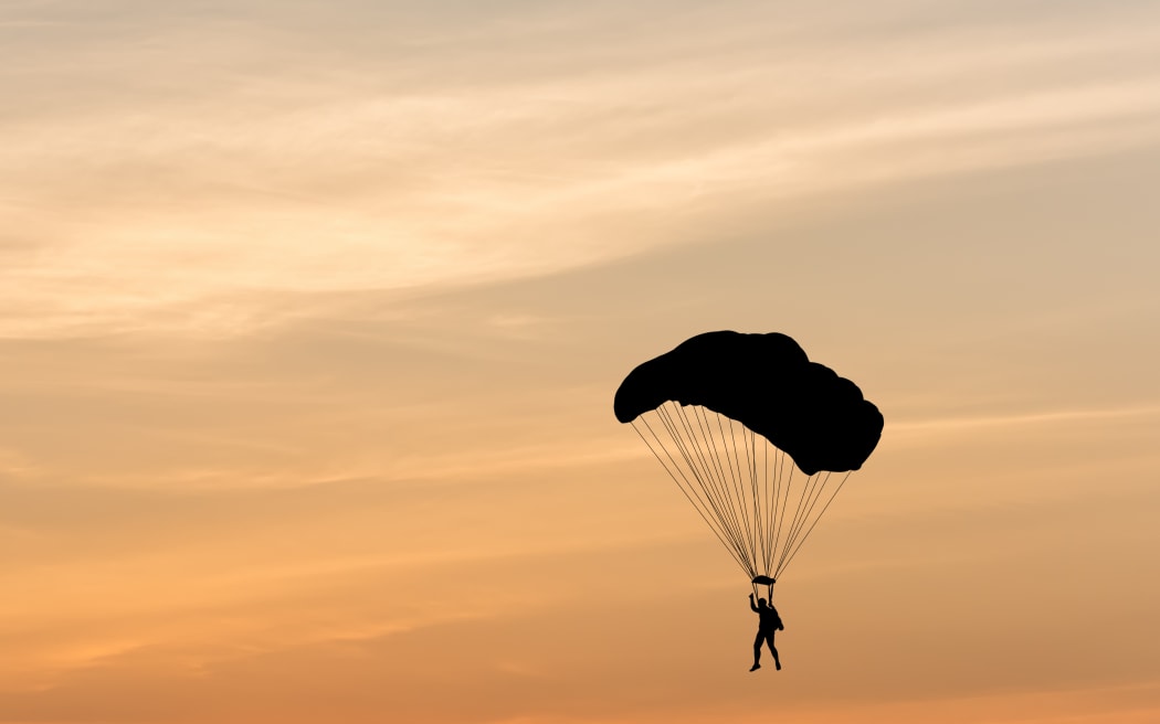Silhouette of a parachute against a background sunset.