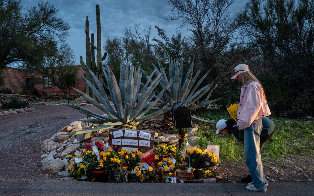 People deliver flowers to a makeshift tribute at Nancy Guthrie's home near Tucson, Arizona, on Thursday, February 12.