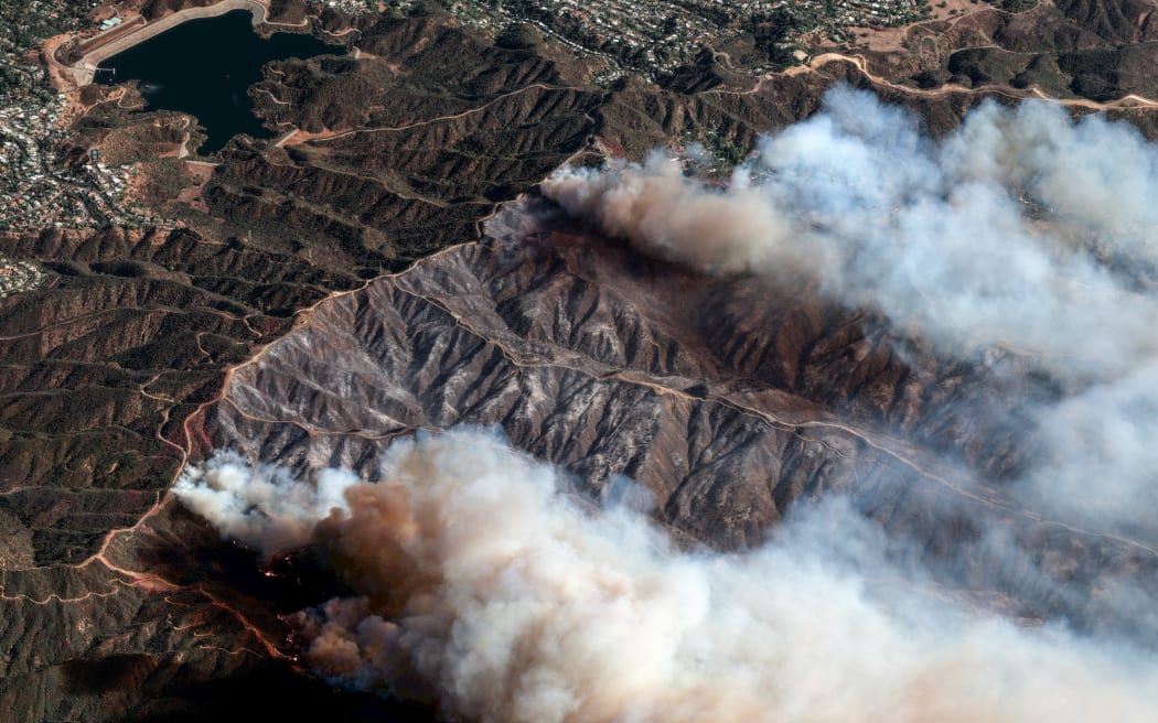 This satellite image taken and released by Maxar Technologies on 11 January 2025 shows an overview of the Palisades Fire as it continues to burn in the mountains north of Santa Monica, California, with the Encino Reservoir in the distance (L). The Palisades Fire, the largest of the Los Angeles fires, spread toward previously untouched neighborhoods January 11, forcing new evacuations and dimming hopes that the disaster was coming under control. Across the city, at least 11 people have died as multiple fires have ripped through residential areas since January 7, razing thousands of homes in destruction that US President Joe Biden likened to a "war scene." (Photo by Satellite image ©2025 Maxar Technologies / AFP) / RESTRICTED TO EDITORIAL USE - MANDATORY CREDIT "AFP PHOTO/ SATELLITE IMAGE ©2025 MAXAR TECHNOLOGIES" - NO MARKETING NO ADVERTISING CAMPAIGNS - DISTRIBUTED AS A SERVICE TO CLIENTS - THE WATERMARK MAY NOT BE REMOVED/CROPPED