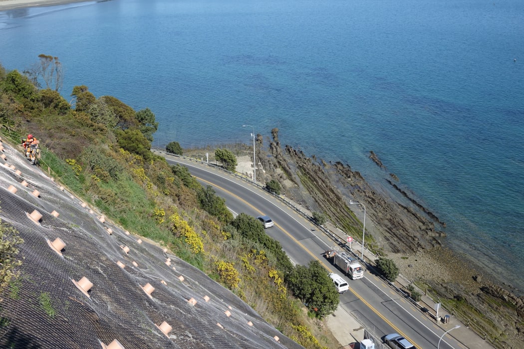 Contractors scale the near vertical slope of the cliffs above Rocks Road
